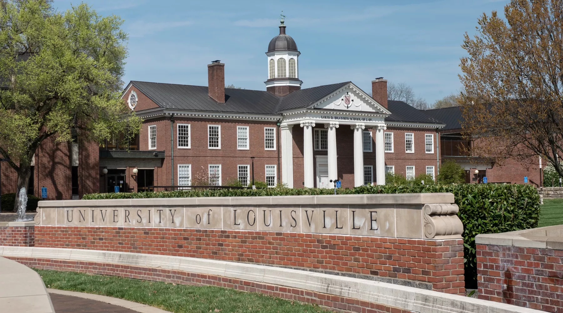 Louis D. Brandeis School of Law building in the background with the main University of Louisville entrance sign on 3rd Street.